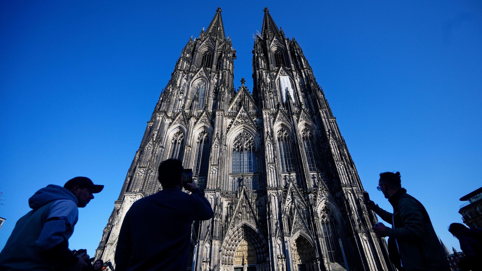 05.03.2026, Nordrhein-Westfalen, Köln: Touristen fotografieren den Kölner Dom. Der Kölner Dom wird Touristen in Zukunft Eintritt kosten. Damit sollen die gestiegenen Kosten für Pflege, Schutz und den laufenden Betrieb des Doms gedeckt werden, wie das Domkapitel auf einer Pressekonferenz mitteilte Foto: Henning Kaiser/dpa +++ dpa-Bildfunk +++