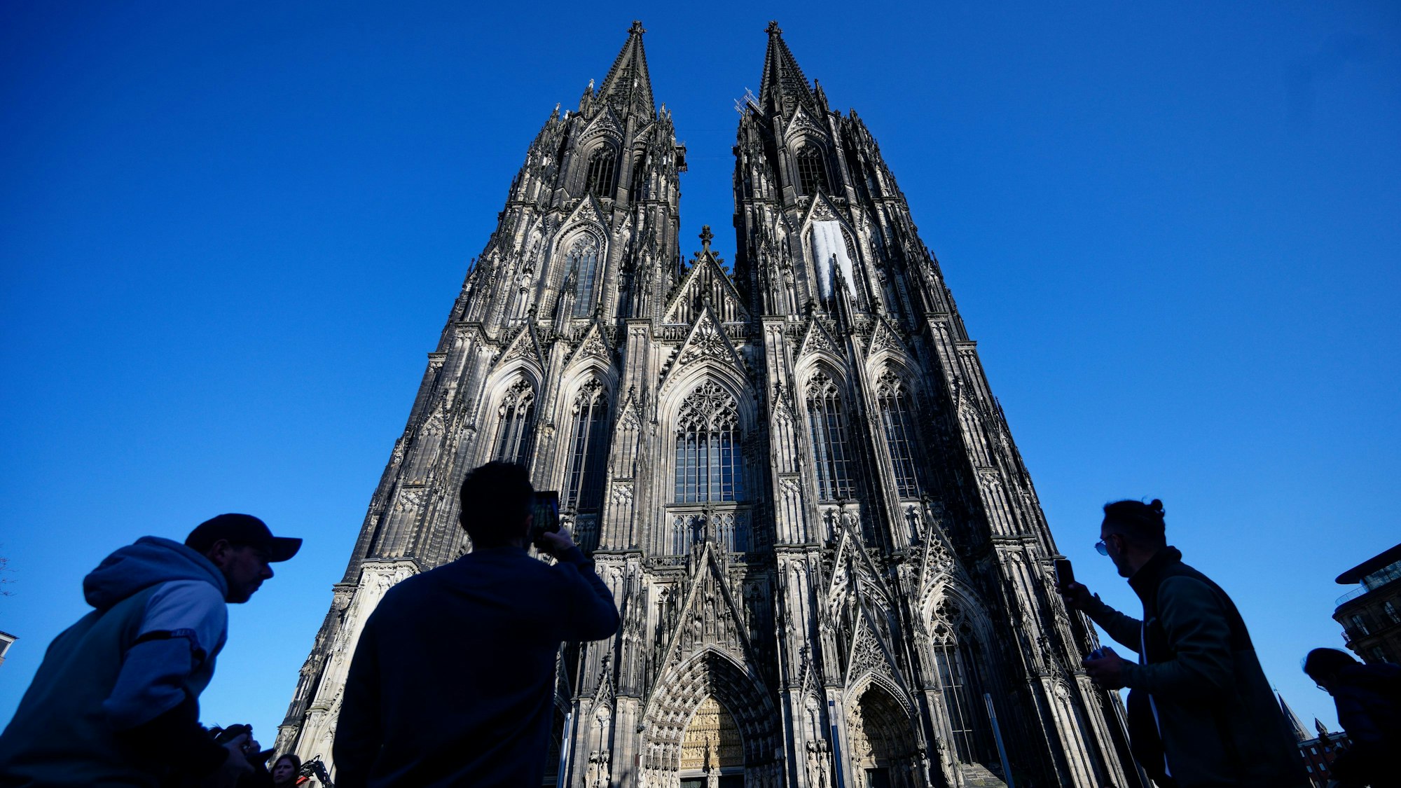 05.03.2026, Nordrhein-Westfalen, Köln: Touristen fotografieren den Kölner Dom. Der Kölner Dom wird Touristen in Zukunft Eintritt kosten. Damit sollen die gestiegenen Kosten für Pflege, Schutz und den laufenden Betrieb des Doms gedeckt werden, wie das Domkapitel auf einer Pressekonferenz mitteilte Foto: Henning Kaiser/dpa +++ dpa-Bildfunk +++