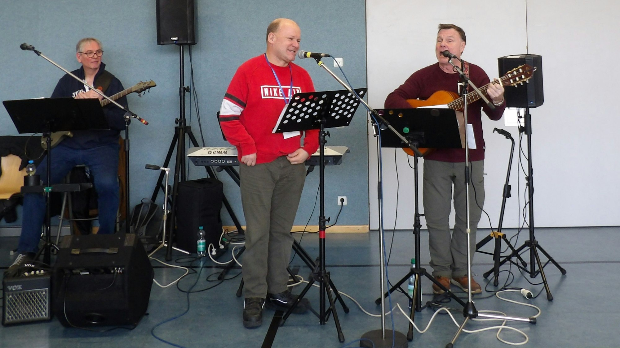 Drei Männer machen Musik in einer Turnhalle.