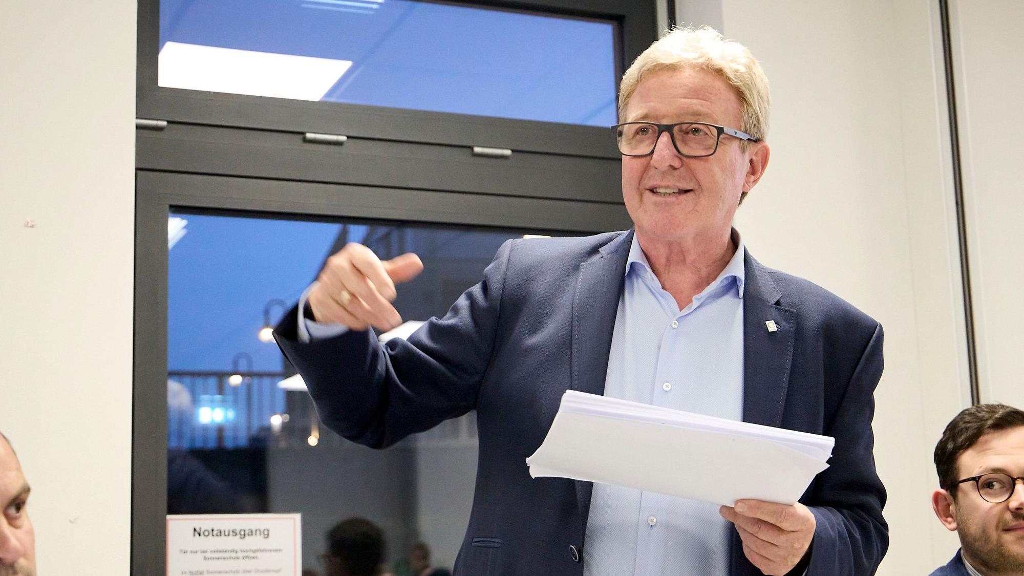 Manfred Poth hält Din-A-4-Blätter in der Hand, während er spricht.