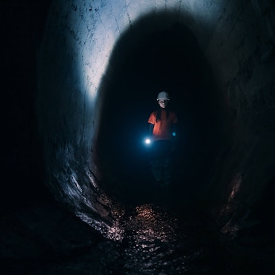 Gräberin mit Taschenlampe erkundet einen Tunnel.