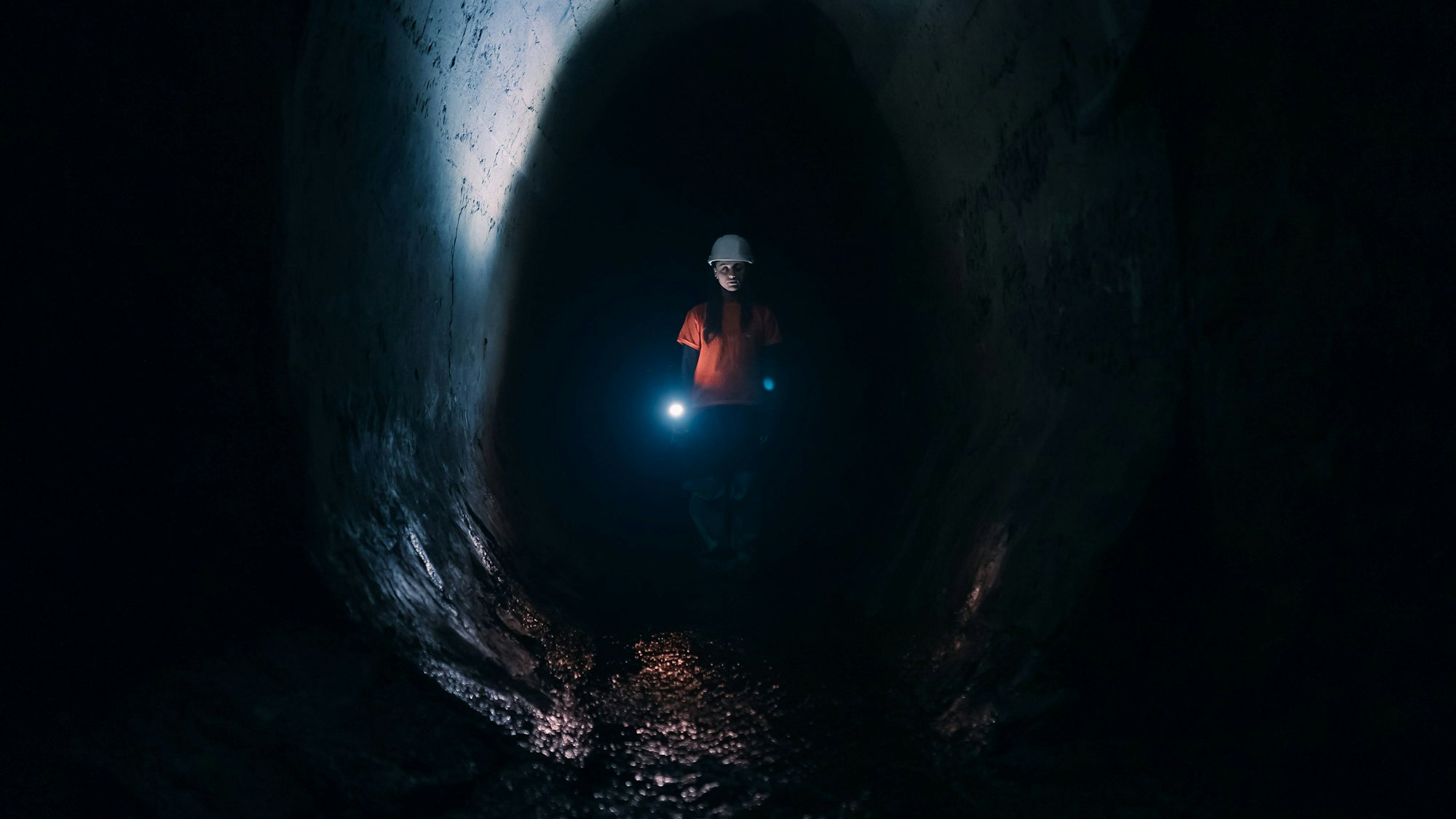 Gräberin mit Taschenlampe erkundet einen Tunnel.