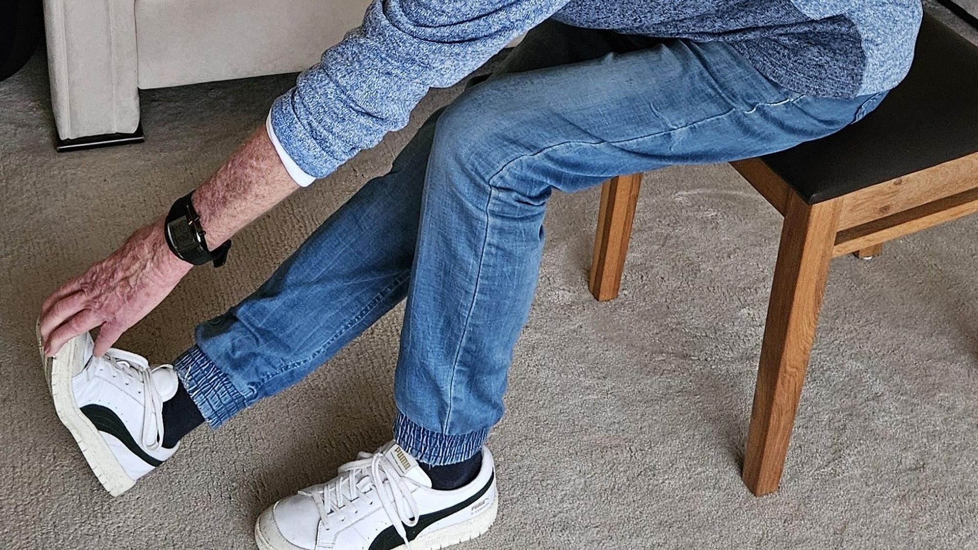 Man sieht eine Hand die sich zu einem Fuß streckt für eine Dehnübung.
