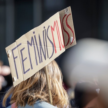 Ein Teilnehmerin einer Demonstration zum Weltfrauentag trägt ein Schild mit der Aufschrift «Feminis-muss».