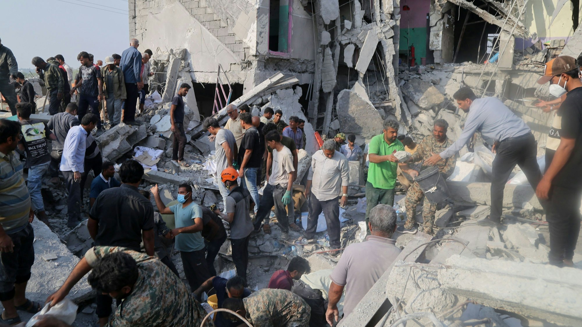 Rettungskräfte und Anwohner durchsuchen die Trümmer nach einem Angriff auf eine Grundschule für Mädchen. (Archivbild)