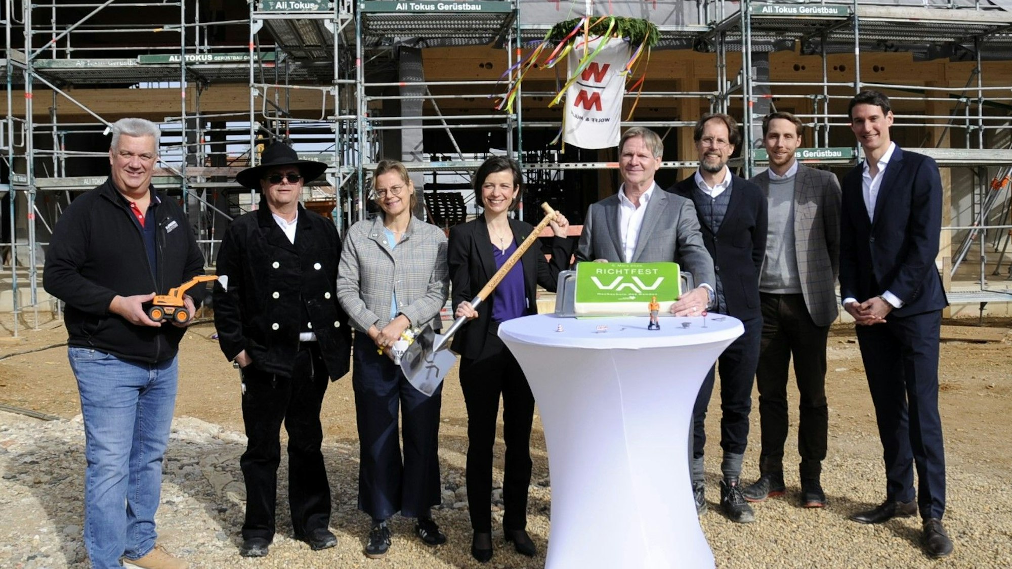 Männer und Frauen stehen vor einem Rohbau.