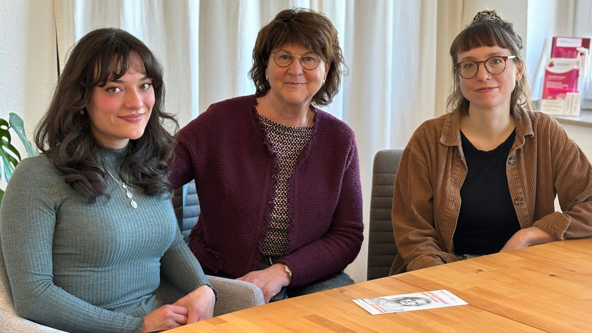 Drei Frauen sitzen an einem Tisch.