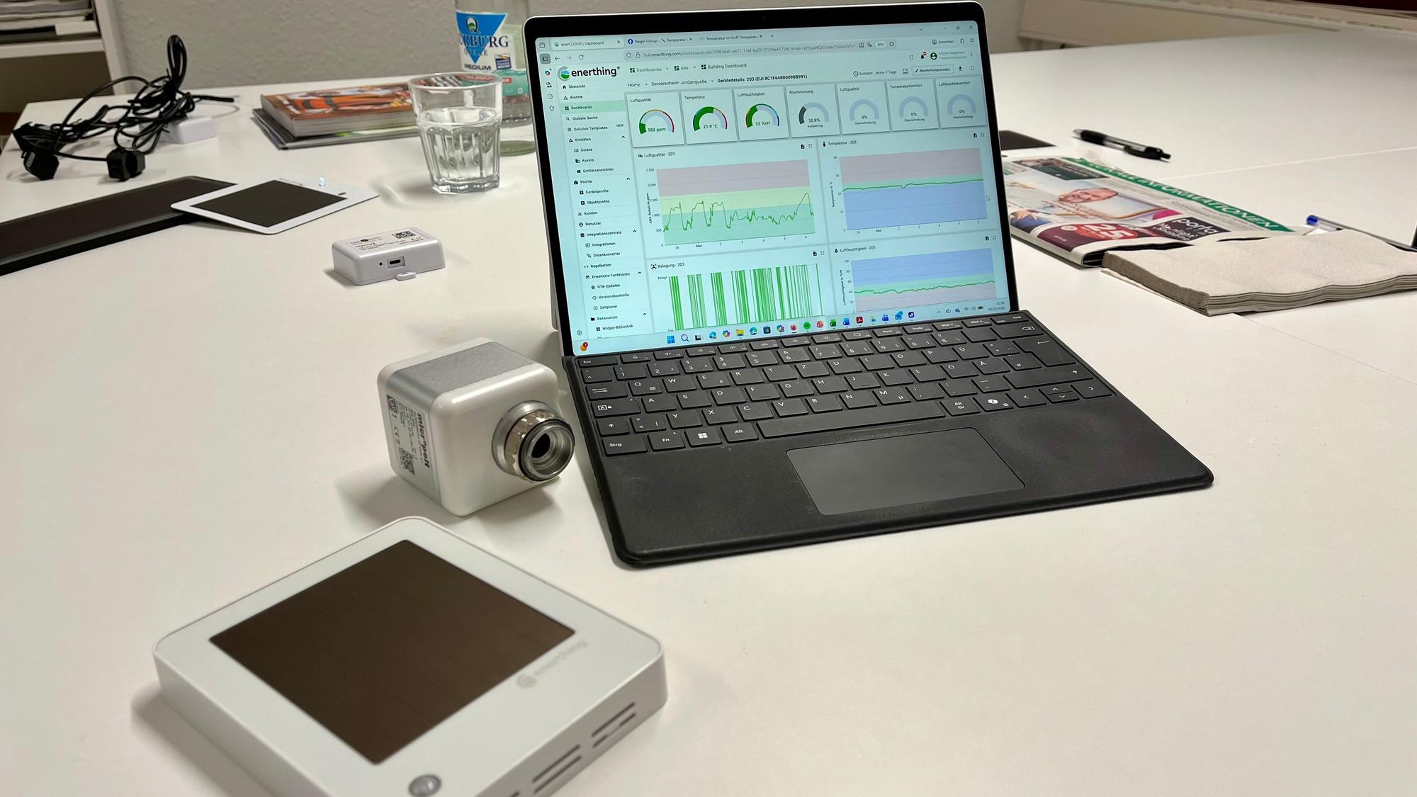 Ein Sensor, ein Thermostat und ein Rechner auf einem Tisch.
