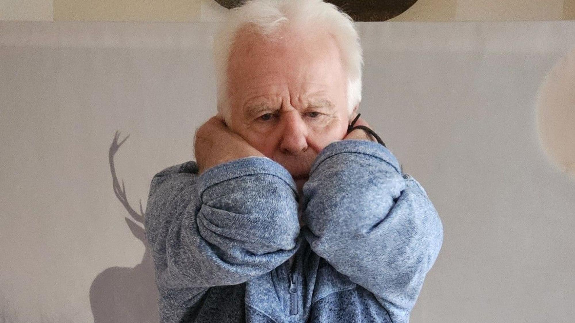 Ein Mann hat die Hände hinten im Nacken und streckt dabei die Ellenbogen nach vorne.