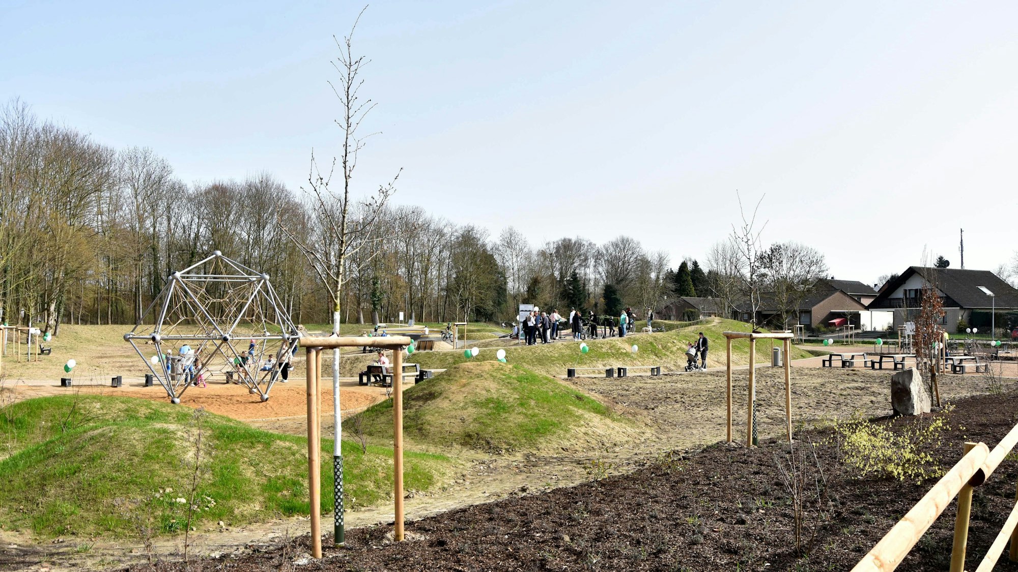 Das Bild zeigt den Sportprk mit Klettergeräten, Bänken und Tischen, im Hintergrund eine Baumreihe.