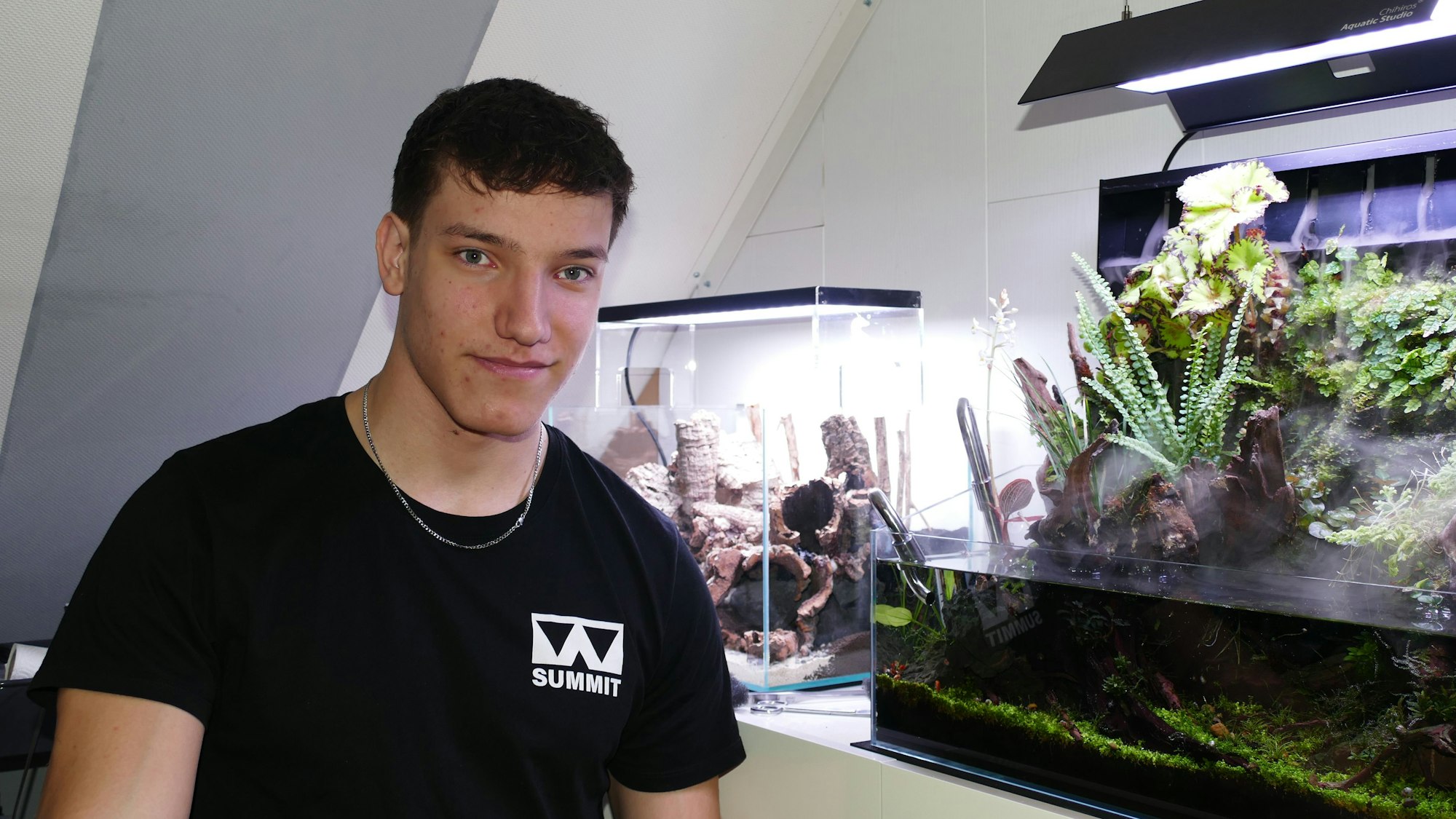 Vico Friedsam steht vor einem Aquarium und lächelt.