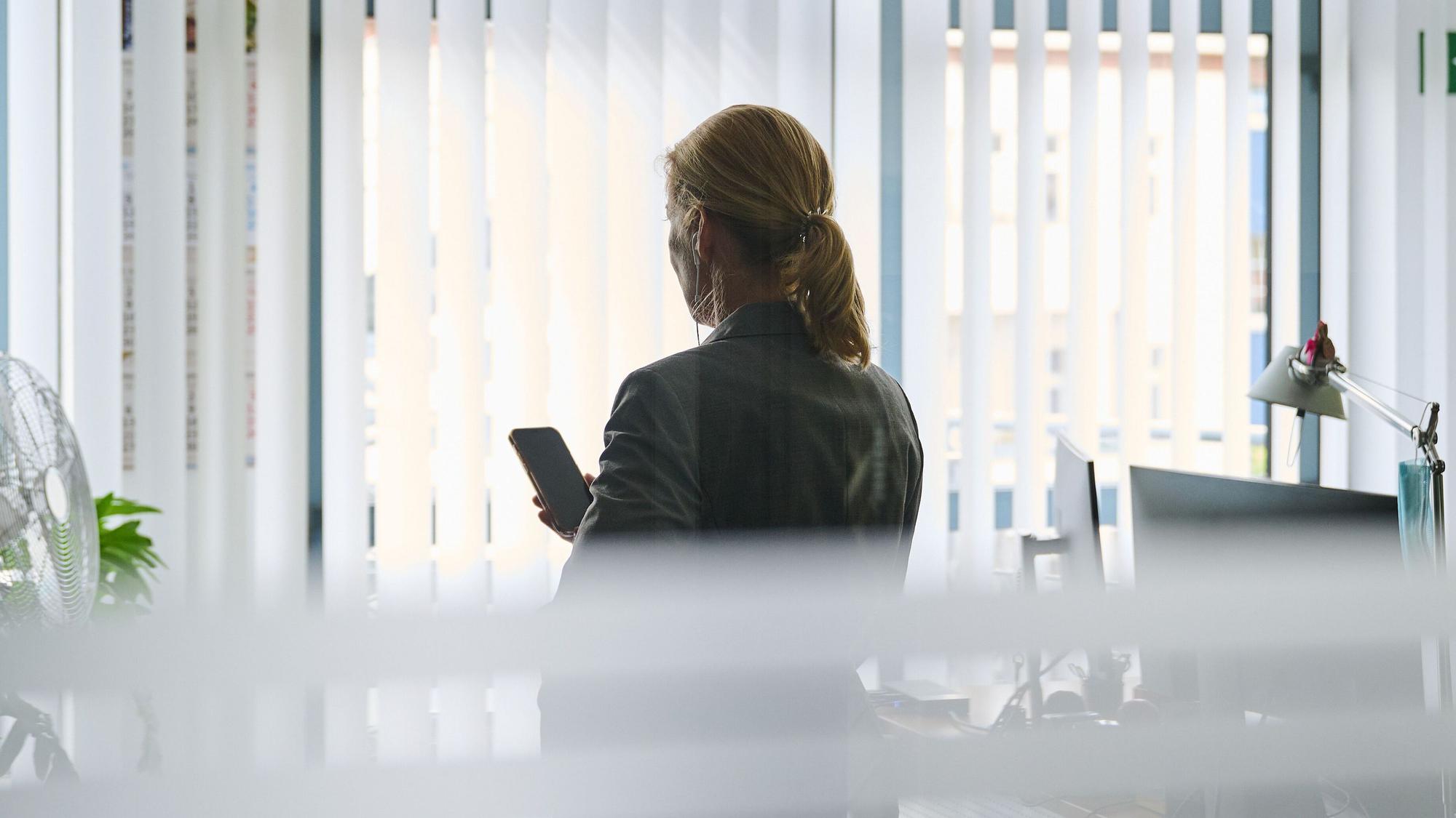 Eine Frau steht in einem Bürozimmer am Fenster und telefoniert über ein Headset. (zu dpa: «Frauen führen deutlich häufiger in Teilzeit als Männer») +++ dpa-Bildfunk +++