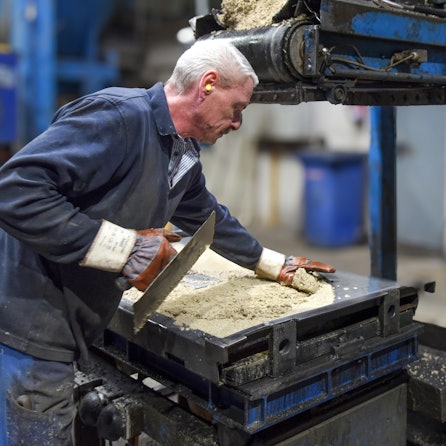 Ein Mitarbeiter fertigt im Gewerbe- und Industriegebiet von Waldbröl-Hermesdorf gerundete Zwischen-Simse aus Beton für die bekannten Gartengrillkamine des Familienunternehmens Buschbeck.