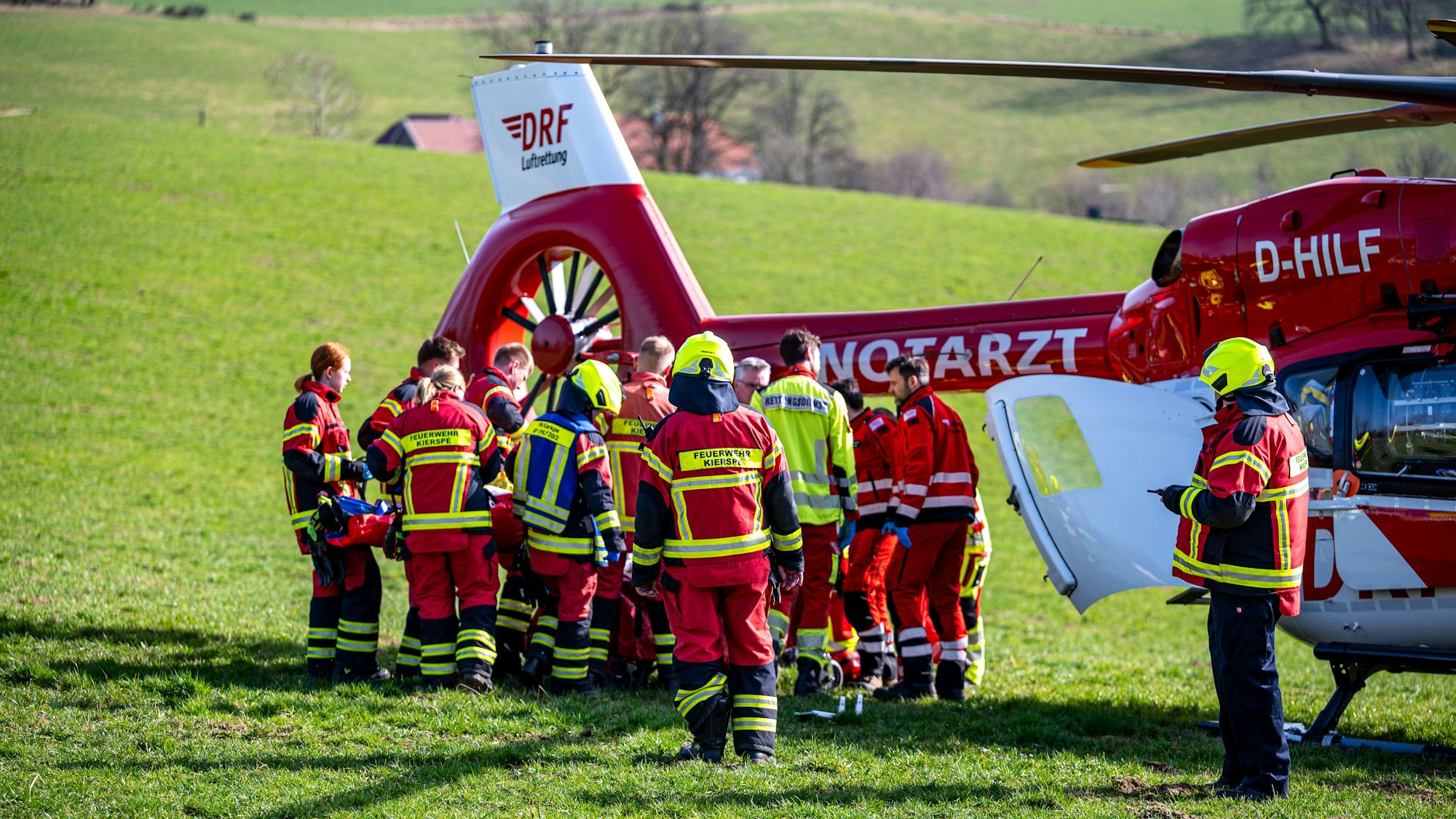 Feuerwehr und Rettungsdienst transportieren einen Verletzten zu einem Rettungshubschrauber.