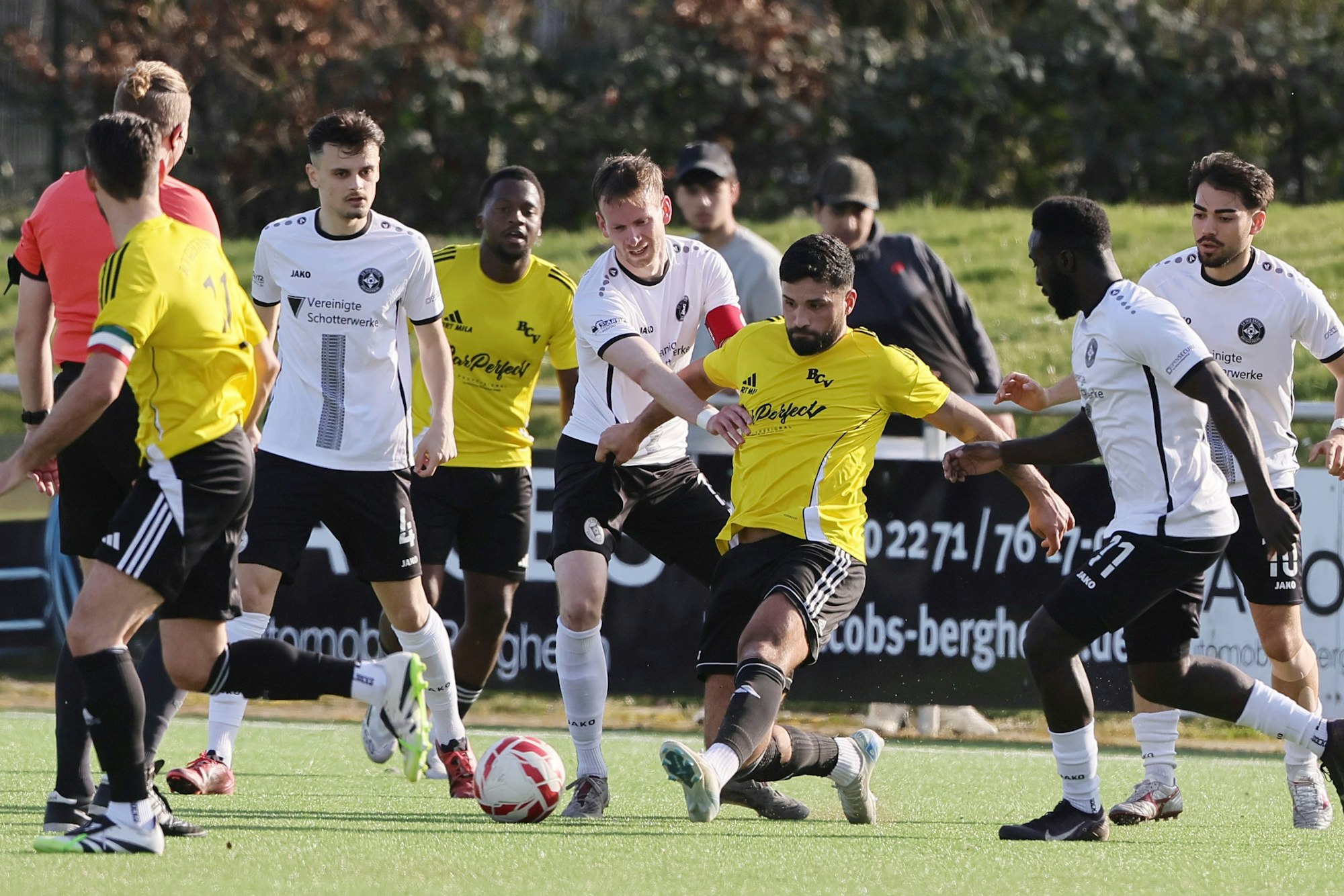 Das Foto zeigt den Glescher Amar Tekin, der das linke Bein zum Ball ausstreckt, umringt von Mit- und Gegenspielern.