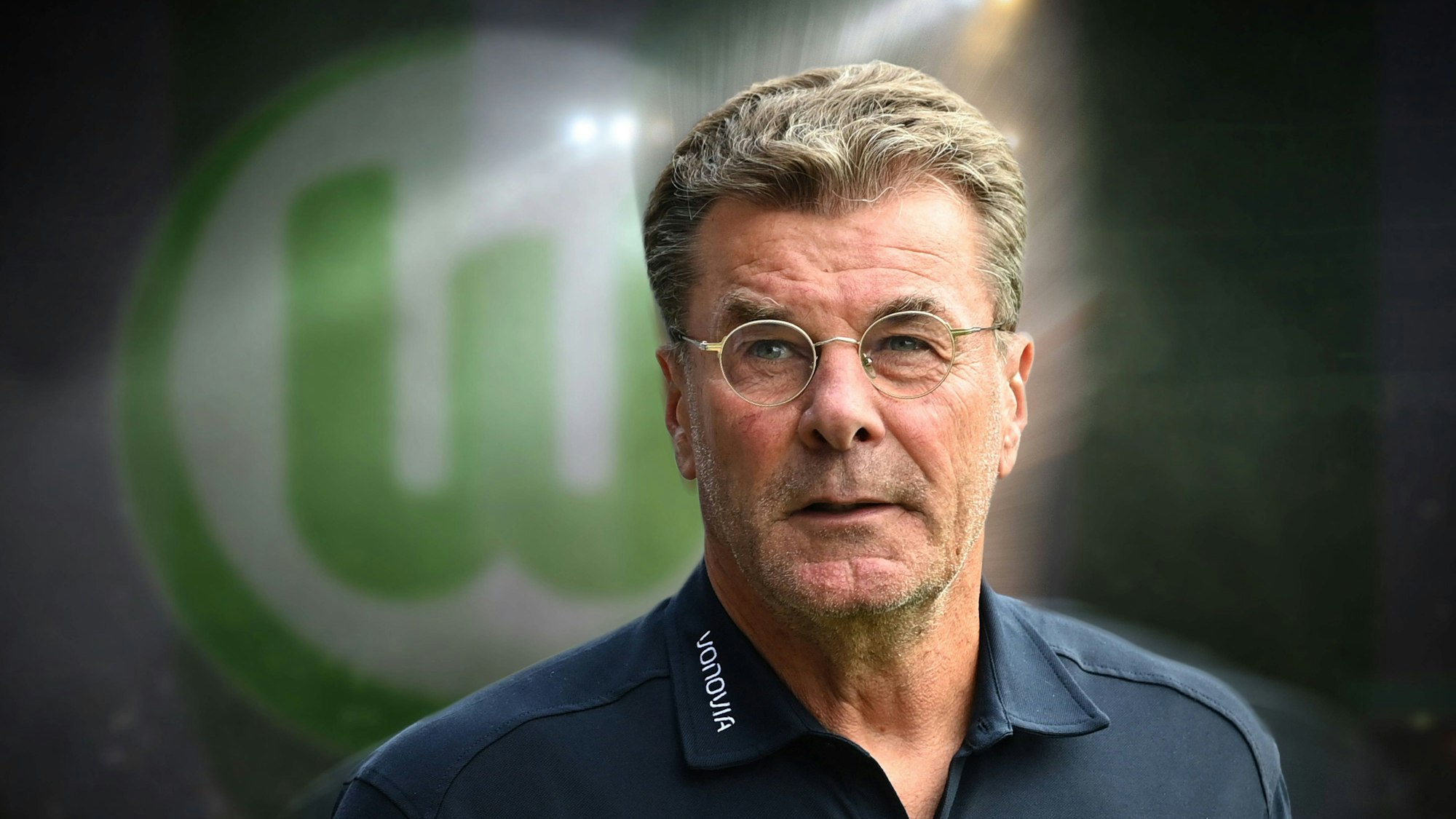 Dieter Hecking auf einer Fotomontage vor dem Logo des VfL Wolfsburg.