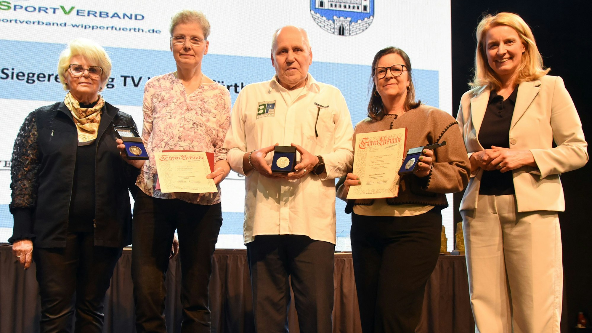 Mehrere Ausgezeichnete stehen bei einem Sportlerabend auf einer Bühne.