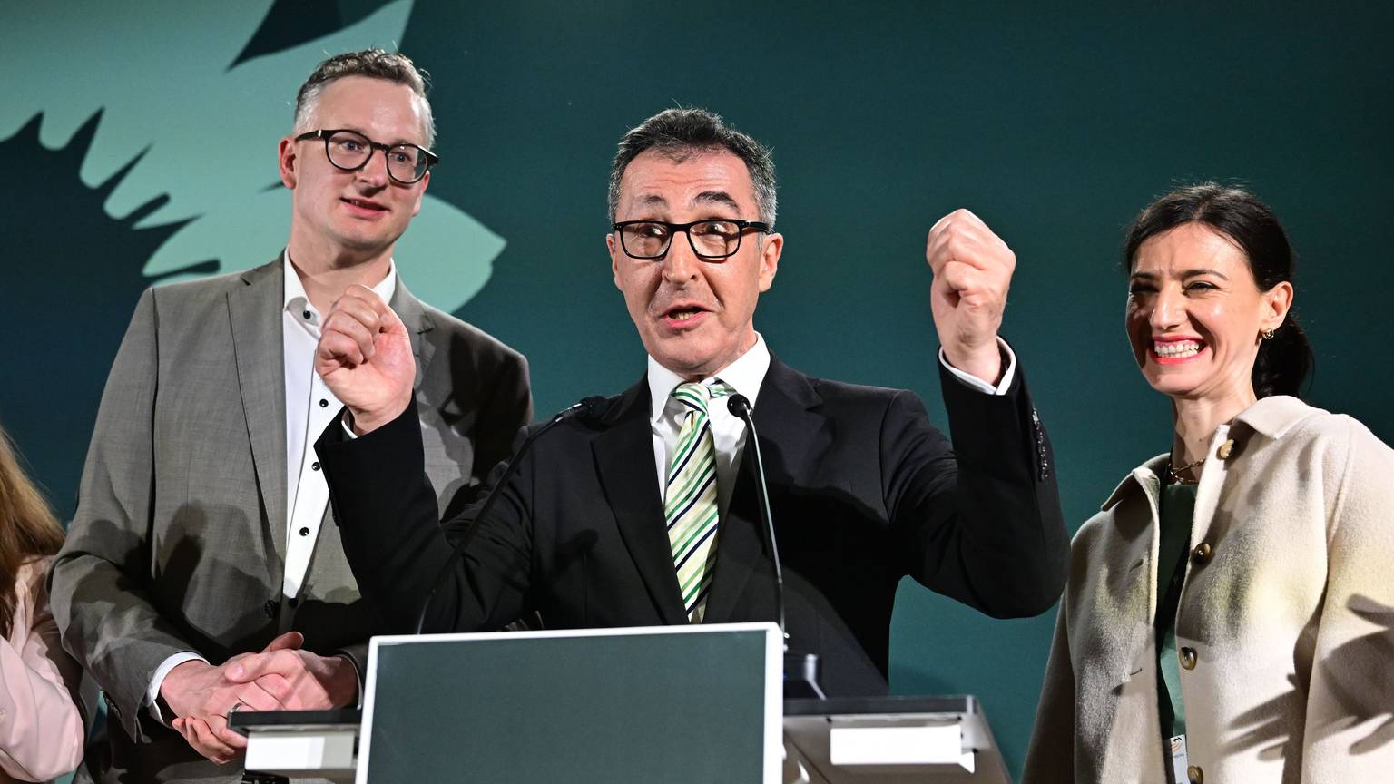 Cem Özdemir (Grüne, Mitte) steht neben Andreas Schwarz (Fraktionsvorsitzender im Landtag) und Flavia Zaka, seiner Frau, bei der Wahlparty in Stuttgart.