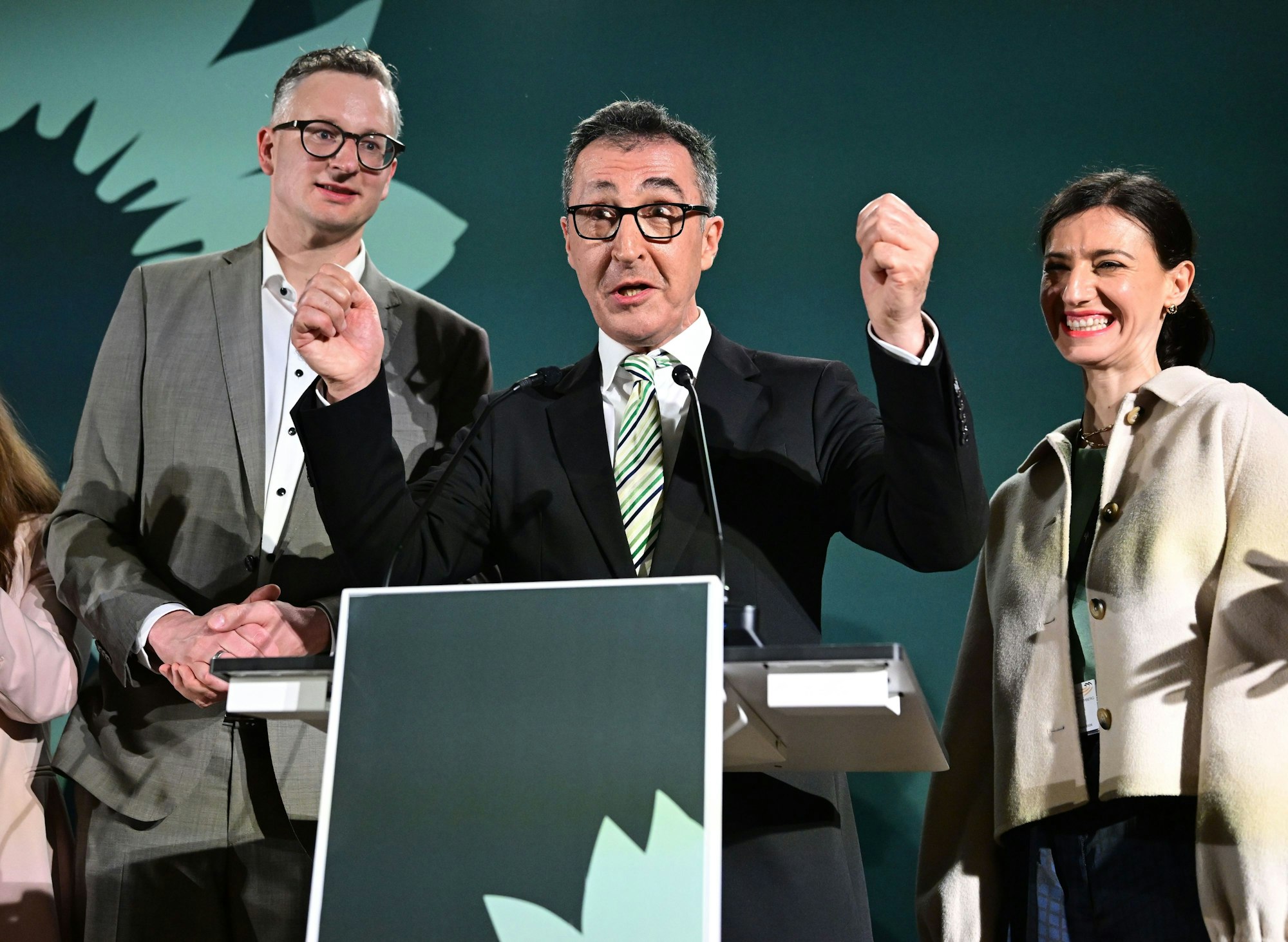 Cem Özdemir (Grüne, Mitte) steht neben Andreas Schwarz (Fraktionsvorsitzender im Landtag) und Flavia Zaka, seiner Frau, bei der Wahlparty in Stuttgart.