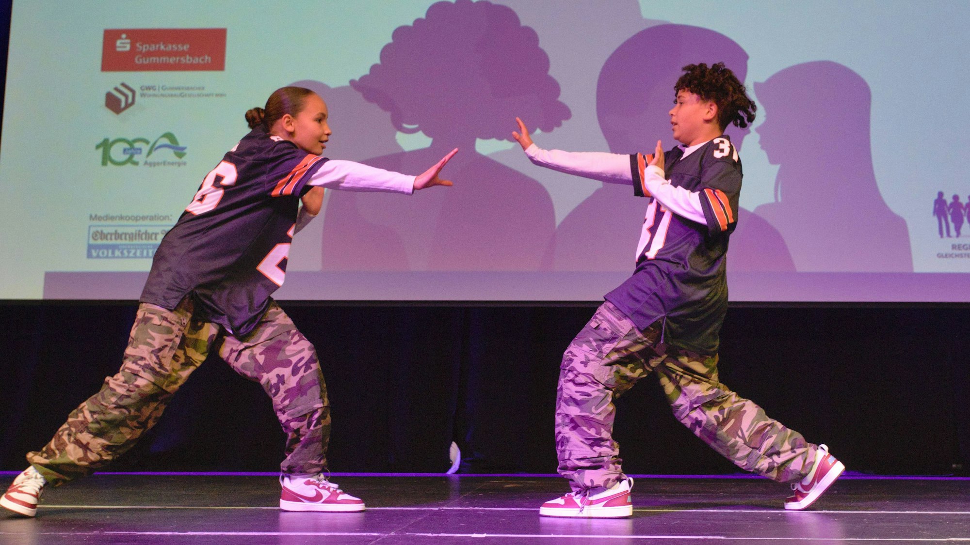 Zwei Geschwister tanzen Hip-Hop auf einer Bühne.