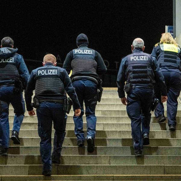 Fünf Menschen mit der Aufschrift „Polizei“ auf ihren Westen gehen eine Treppe hoch.