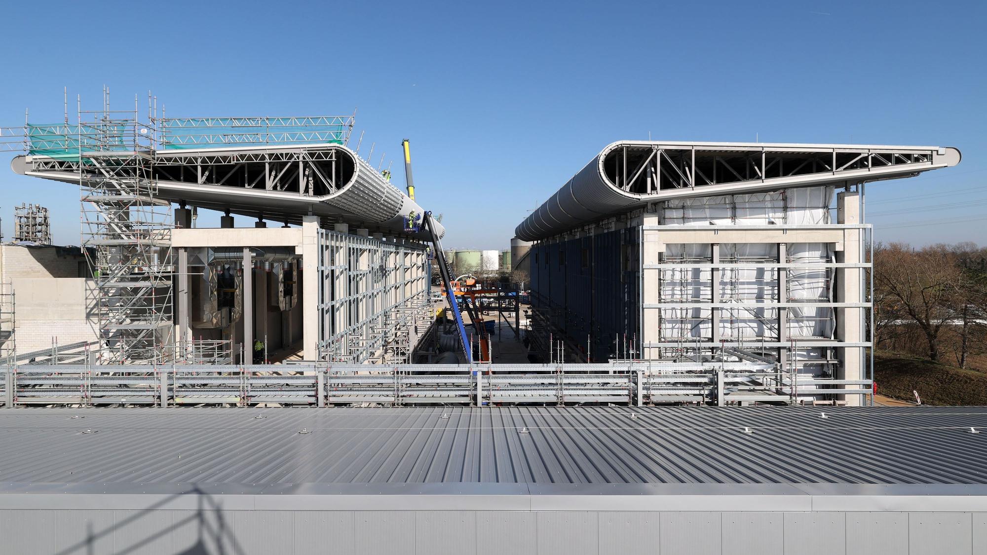 Der Rohbau von Refhyne 2 steht. Markant sind die flügelartigen Dächer, in denen der Sauerstoff, der bei der Elektrolyse als Nebenprodukt entsteht, aufgefangen wird.
