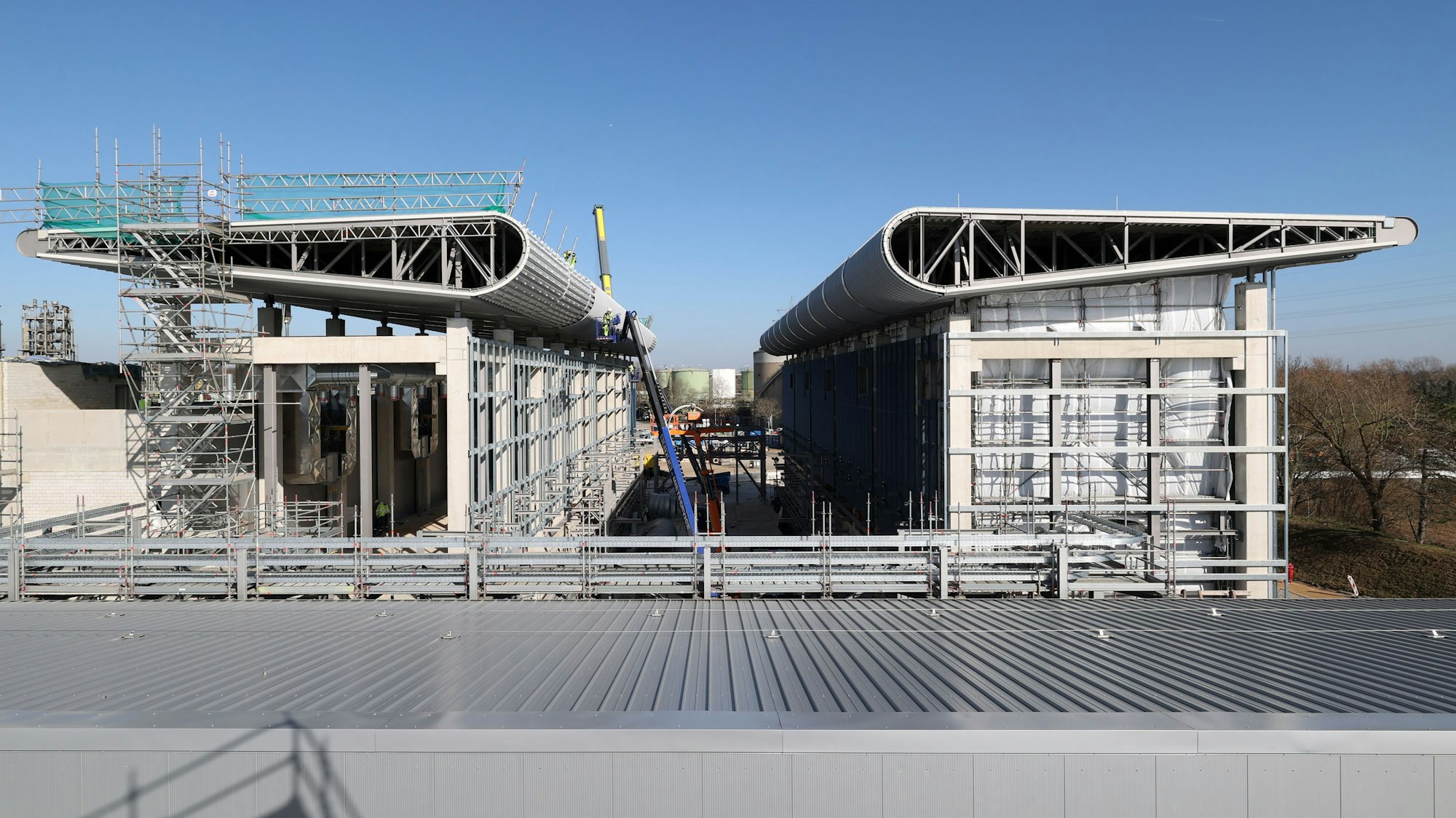 Der Rohbau von Refhyne 2 steht. Markant sind die flügelartigen Dächer, in denen der Sauerstoff, der bei der Elektrolyse als Nebenprodukt entsteht, aufgefangen wird.