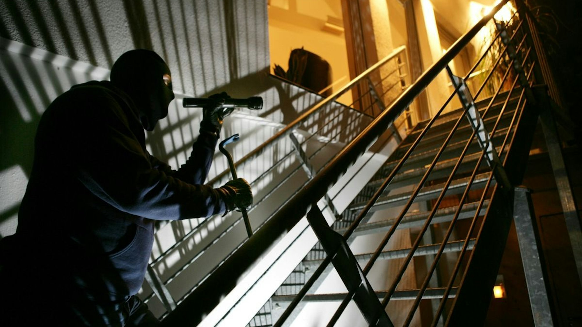Einbrecher mit Brecheisen auf einer Treppe. (Symbolbild)