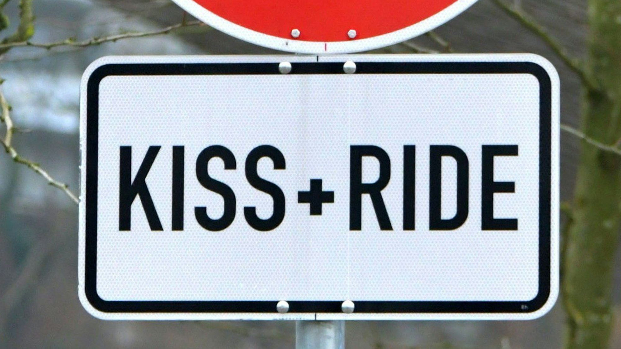 Das Foto zeigt ein Schild mit der Aufschrift „Kiss + Ride“.
