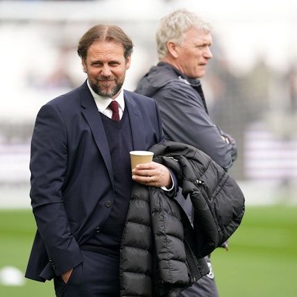 Tim Steidten mit einem Becher in der Hand, im Hintergrund steht Trainer David Moyes.