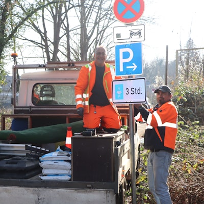 Das Bild zeigt Arbeiter an einem, einer auf einem LKW, die an den erwähnten Schildern werkeln.