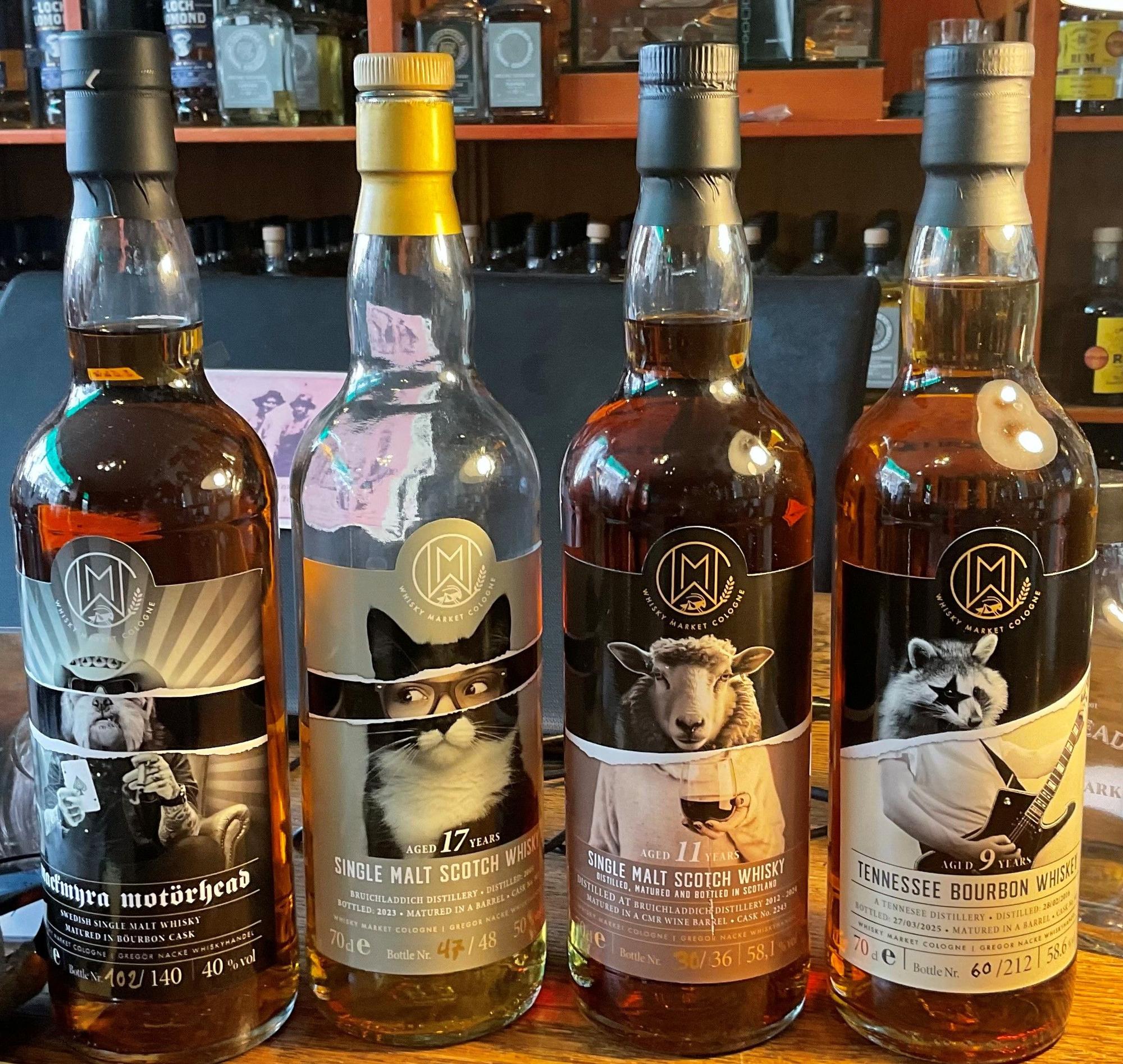Vier Whisky- oder Bourbon-Flaschen stehen nebeneinander.
