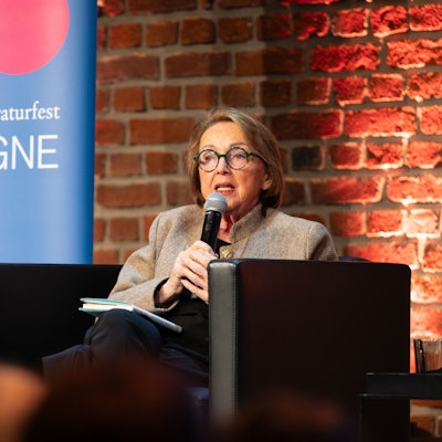 Eine ältere Frau spricht in ein Mikrofon.