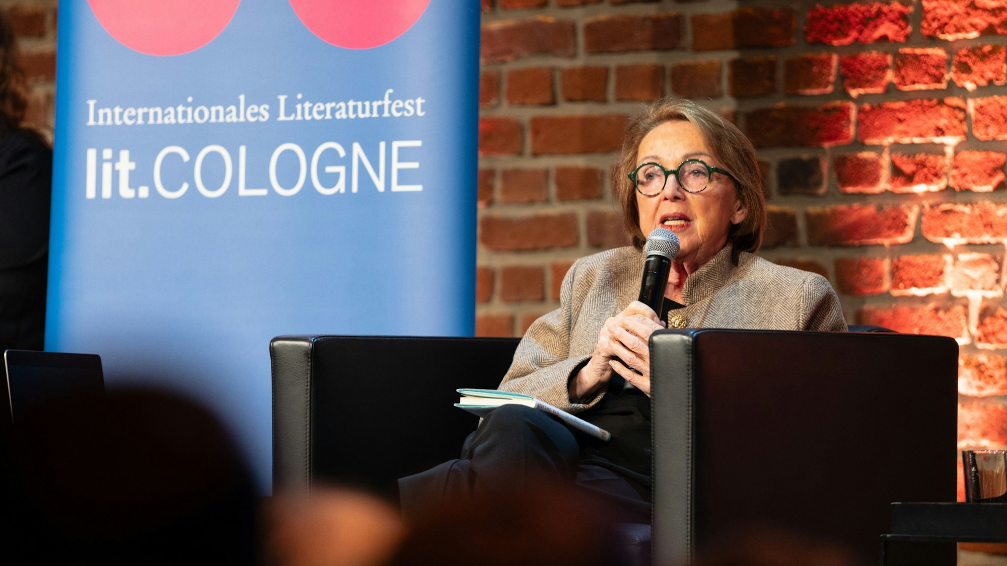 Eine ältere Frau spricht in ein Mikrofon.