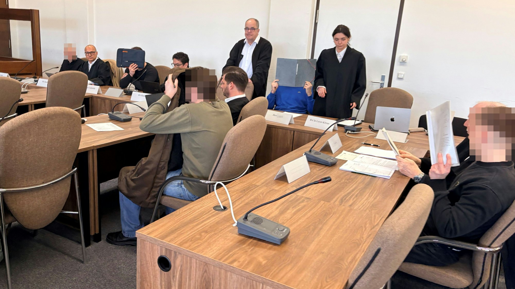Die fünf Angeklagten mit ihren Verteidigern beim Prozessauftakt in Saal 112 des Kölner Landgerichts