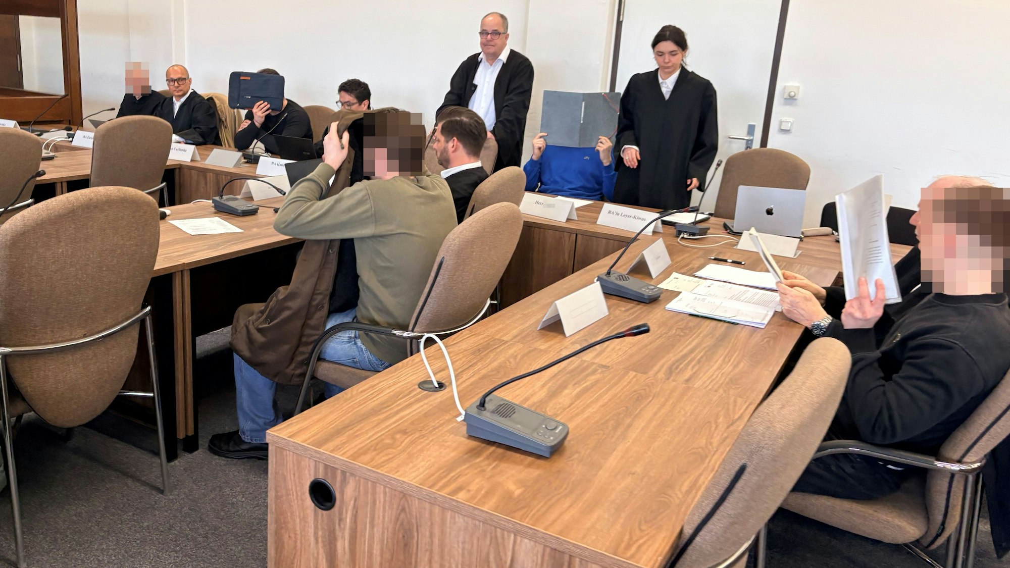Die fünf Angeklagten mit ihren Verteidigerinnen beim Prozessauftakt in Saal 112 des Kölner Landgerichts