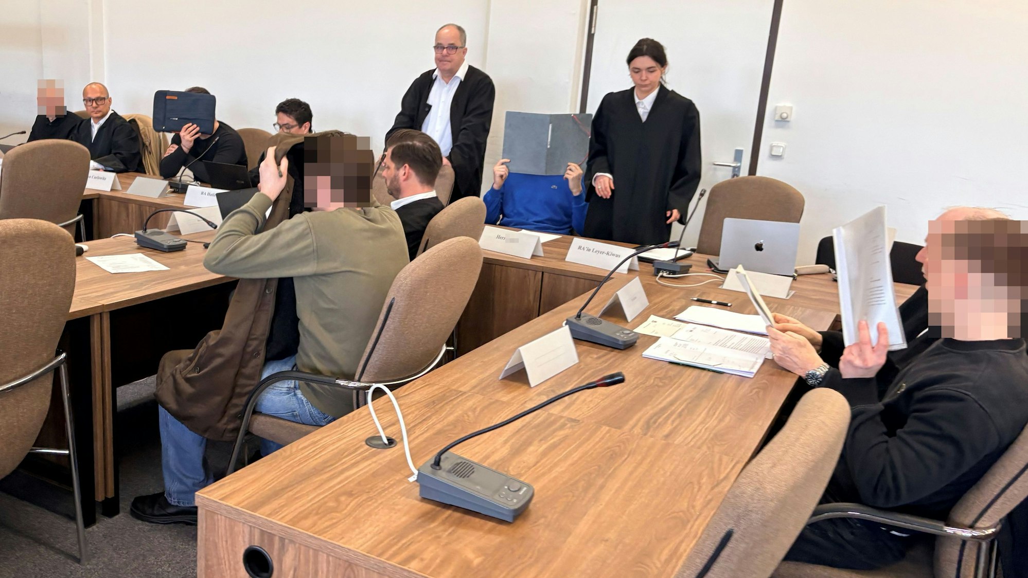 Die fünf Angeklagten mit ihren Verteidigerinnen beim Prozessauftakt in Saal 112 des Kölner Landgerichts