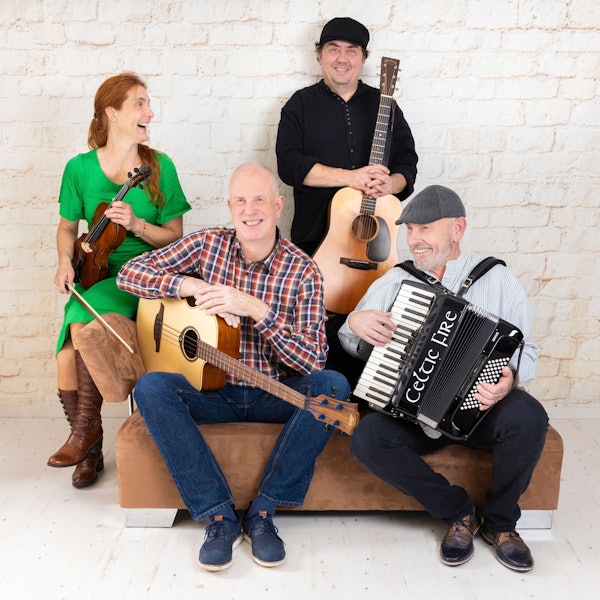 Die vierköpfige Band Celtic Fire steht und sitzt mit ihren Instrumenten an und auf einem Sofa.