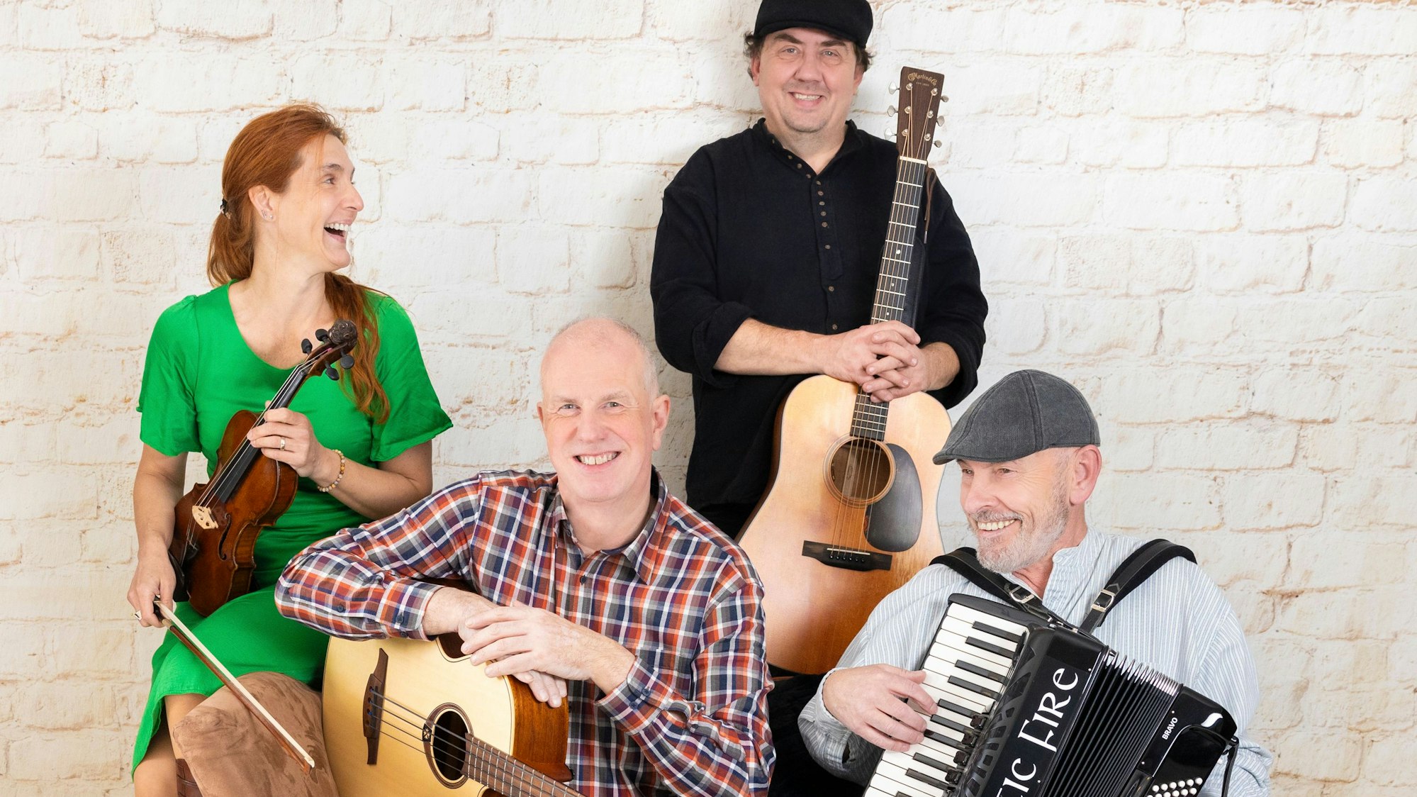 Die vierköpfige Band Celtic Fire steht und sitzt mit ihren Instrumenten an und auf einem Sofa.