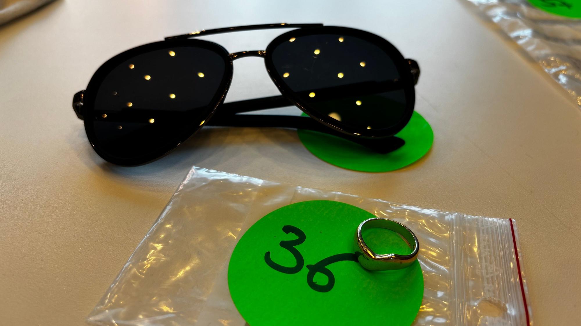 Silberring und Sonnenbrille liegen auf einem Tisch.
