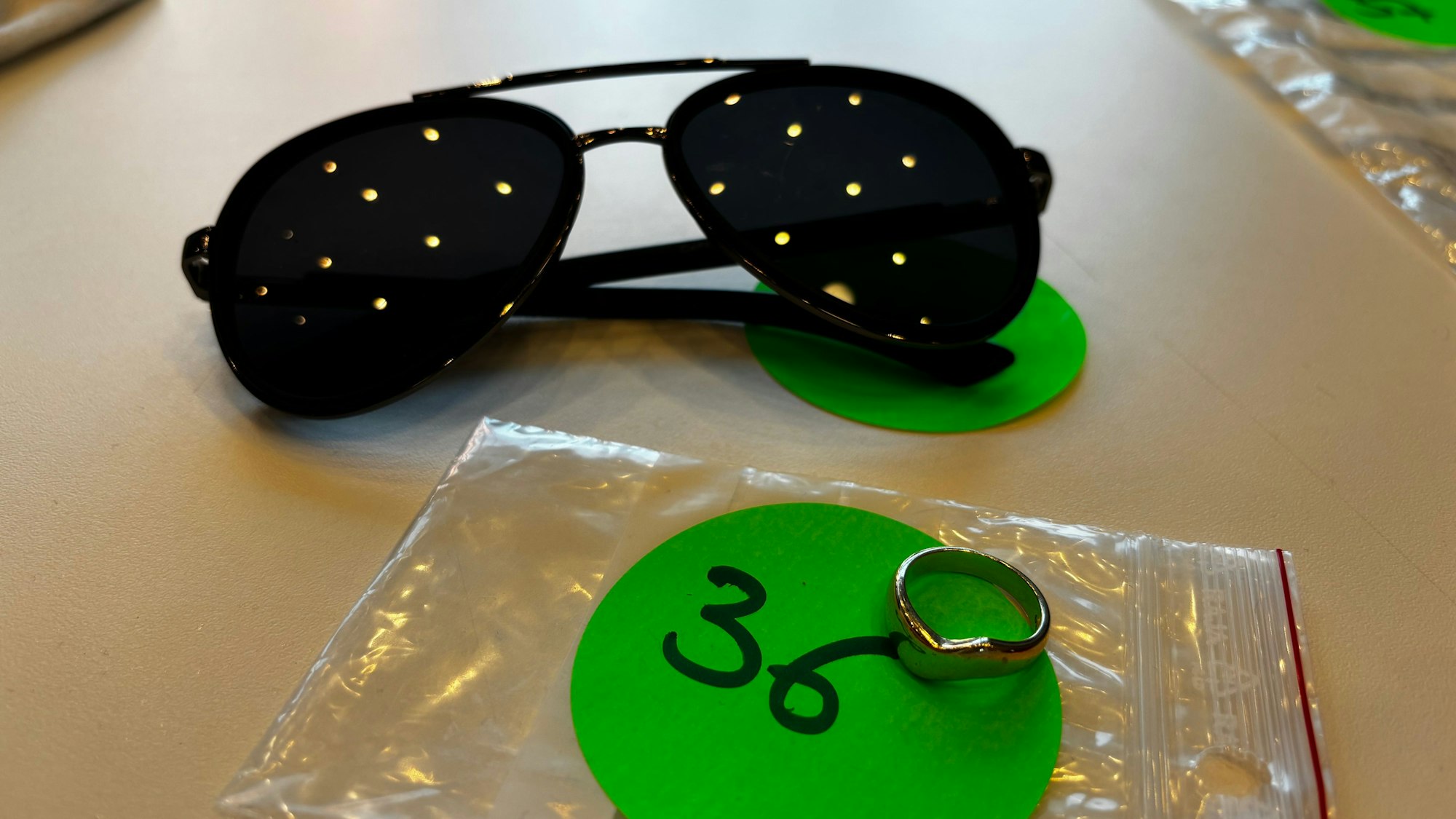 Silberring und Sonnenbrille liegen auf einem Tisch.