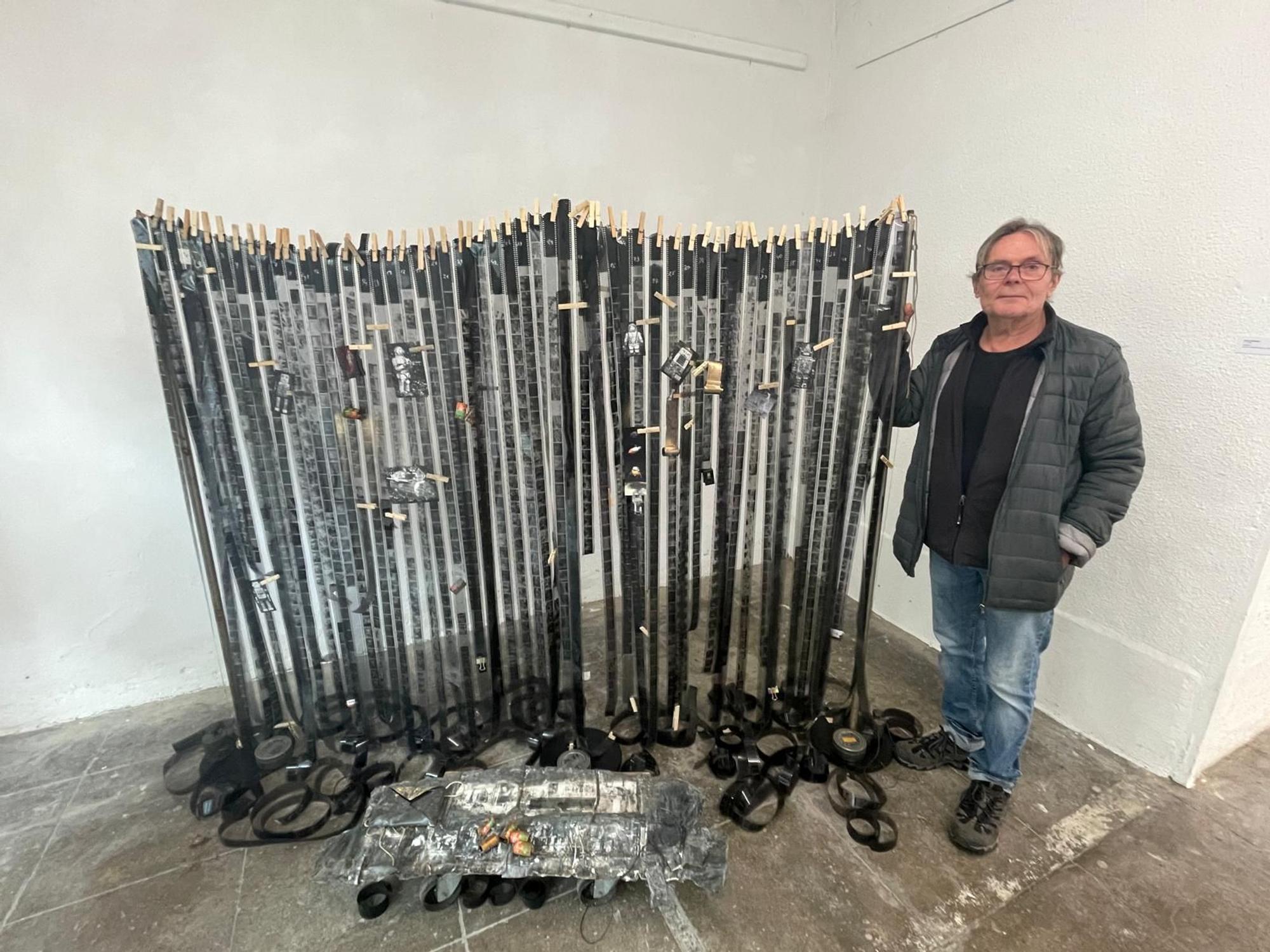 Jürgen Dehniger steht neben seiner Installation aus Filmrollen