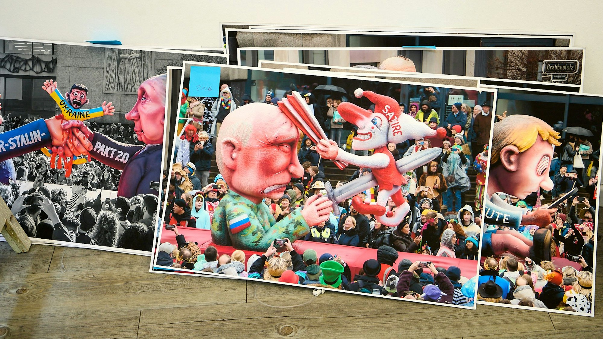 Fotos, die im Stapel an die Wand gelehnt sind, zeigen Szenen aus Rosenmontgszügen mit Tillys Wagen.