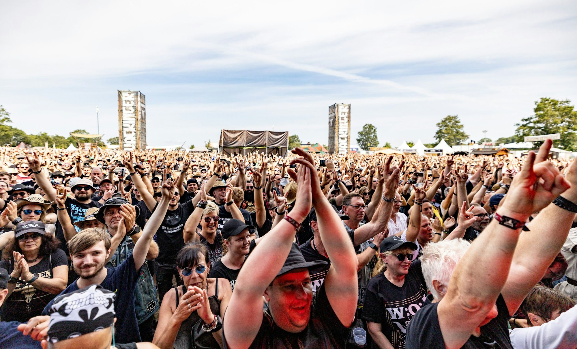 31.07.2024, Schleswig-Holstein, Wacken: Besucher des Wacken Open Air feiern vor der Bühne während des Auftritts der ·Wacken Firefighters· die mit ihrem Konzert das Festival eröffnen. Das WOA gilt als größtes Heavy-Metal-Festival der Welt. Foto: Axel Heimken/dpa - ACHTUNG: Nur zur redaktionellen Verwendung im Zusammenhang mit der aktuellen Berichterstattung und nur mit vollständiger Nennung des vorstehenden Credits KEIN ARCHIV NO SALES +++ dpa-Bildfunk +++