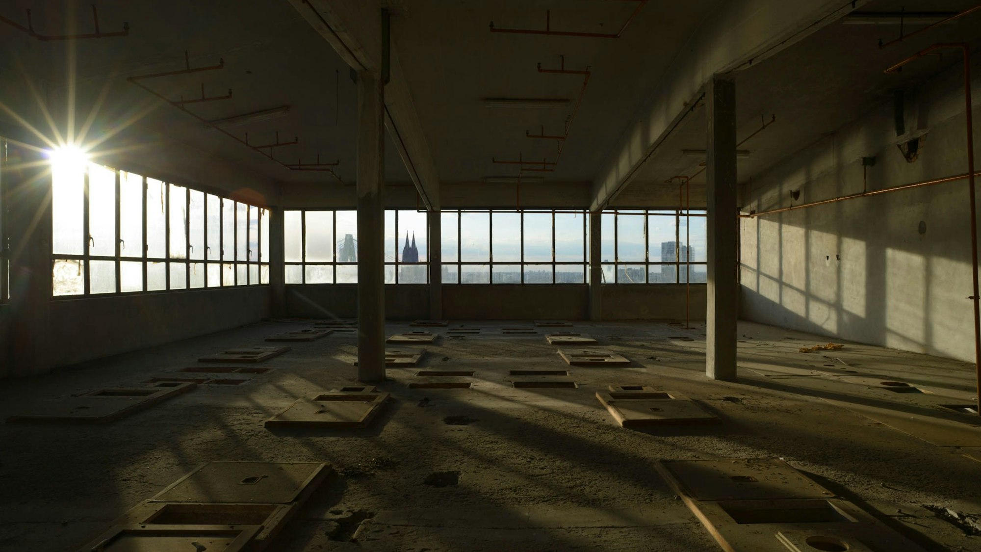 Eine leere Fabriketage. Durch ein Fenster sind die Domspitzen zu sehen.