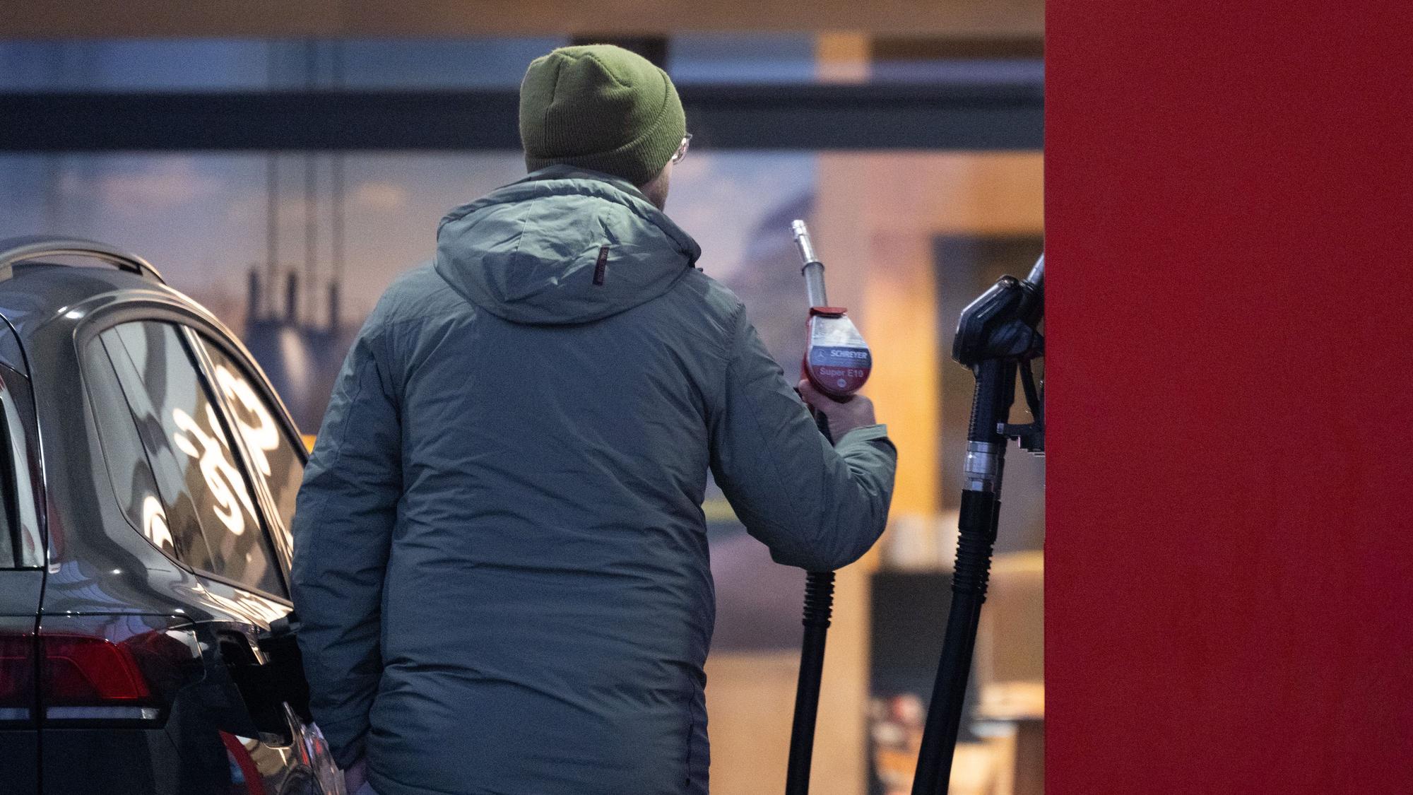 Ein Mann hält an einer Tankstelle eine Zapfpistole. (Symbolfoto)