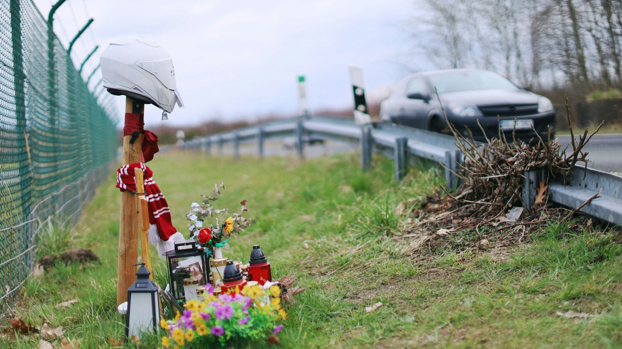 Auf der Alten Kölner Straße am Flughafen, wo im Sommer 2025 zwei junge Motorradfahrer bei einem tragischen Unfall starben, erinnert unter anderem ein Kreuz an eines der Opfer.
