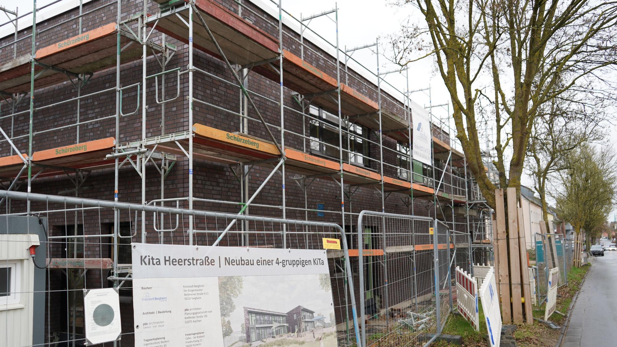 Das Bild zeigt die Baustelle der Kita an der Heerstraße, vor dem Gebäude sind Bauzäune, am Gebäude sind Gerüste zu sehen.