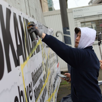 11.03.2026, Köln: Die Kölner Bühnen haben rund um die Opernbaustelle einen als Frustzaun bezeichneten Bauzaun geschaffen, der mit zahlreichen negativen Schlagzeilen rund um die Sanierung beklebt ist. In einer Künstlerischen Aktion soll der Zaun jetzt umgestaltet werden. Foto: Arton Krasniqi