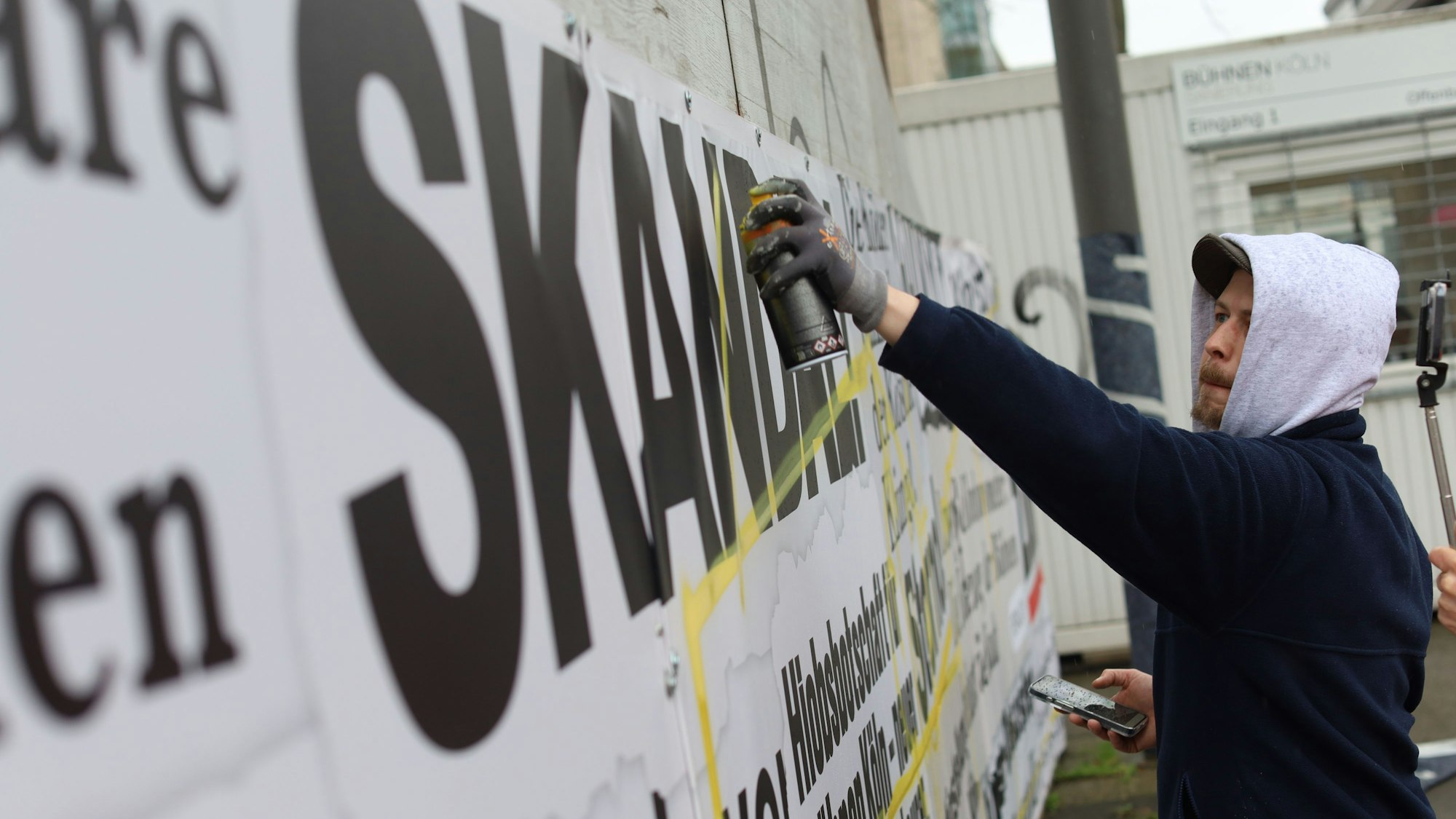 11.03.2026, Köln: Die Kölner Bühnen haben rund um die Opernbaustelle einen als Frustzaun bezeichneten Bauzaun geschaffen, der mit zahlreichen negativen Schlagzeilen rund um die Sanierung beklebt ist. In einer Künstlerischen Aktion soll der Zaun jetzt umgestaltet werden. Foto: Arton Krasniqi